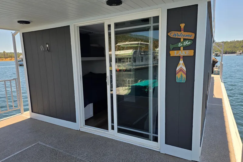 Slide: The Image of Houseboat with sliding glass door, "Welcome to the Lake" sign, docked on a sunny day. - 3