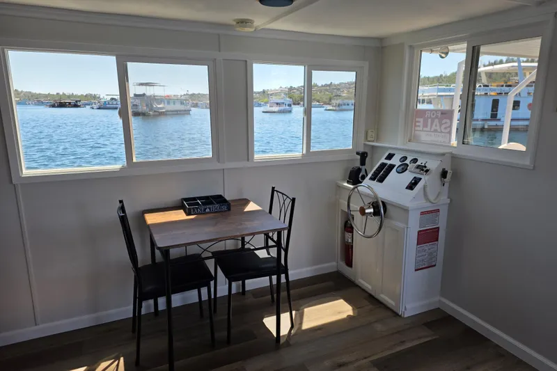 Slide: The Image of Interior of a 2007 custom houseboat with dining table and helm, overlooking a serene lake. - 9