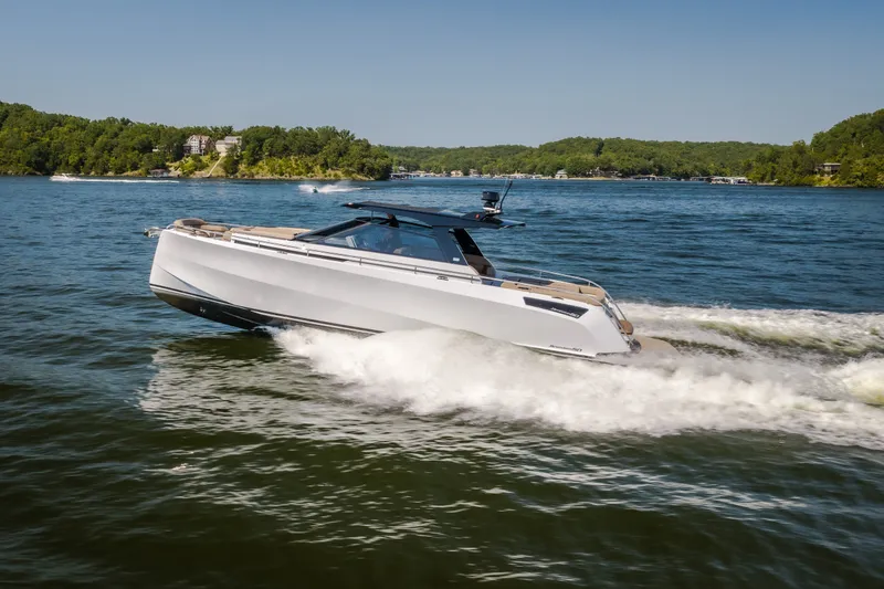 The Image of 2022 Steeler Bronson 50 yacht cruising on a scenic lake with lush green shoreline. - 0