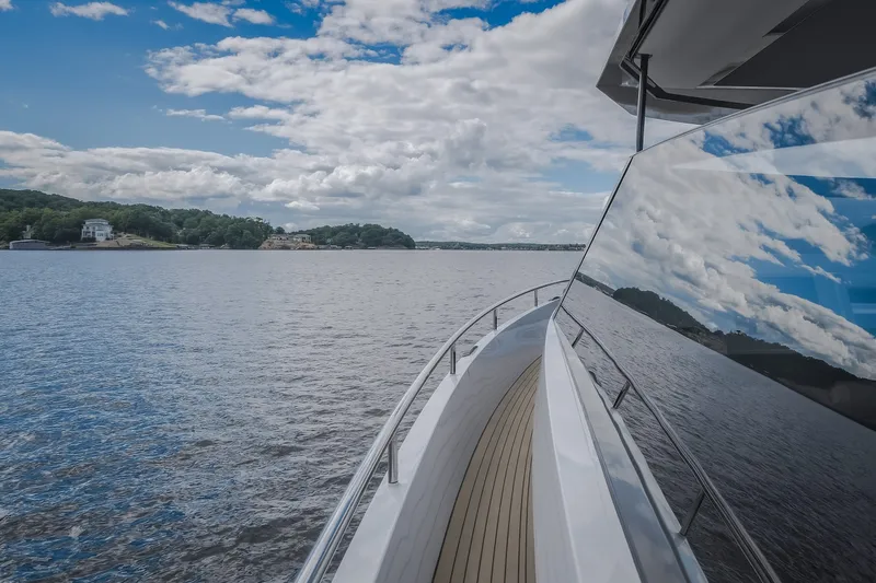 Slide: The Image of 2022 Steeler Bronson 50 yacht cruising on a serene lake under a partly cloudy sky. - 45