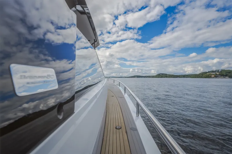 Slide: The Image of 2022 Steeler Bronson 50 yacht cruising on a scenic lake under a partly cloudy sky. - 24