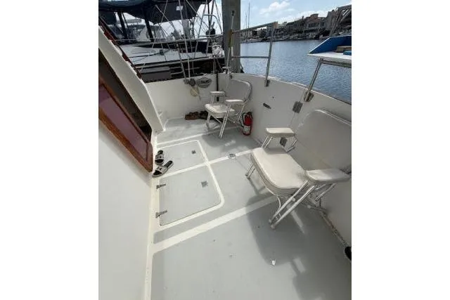 Slide: The Image of 1982 Lancer 45 Motorsailer cockpit with folding chairs, docked by the water. - 28