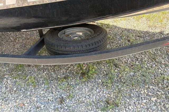 Slide: The Image of 2023 Tracker Pro Team 175 TXW boat trailer with spare tire on gravel surface. - 10