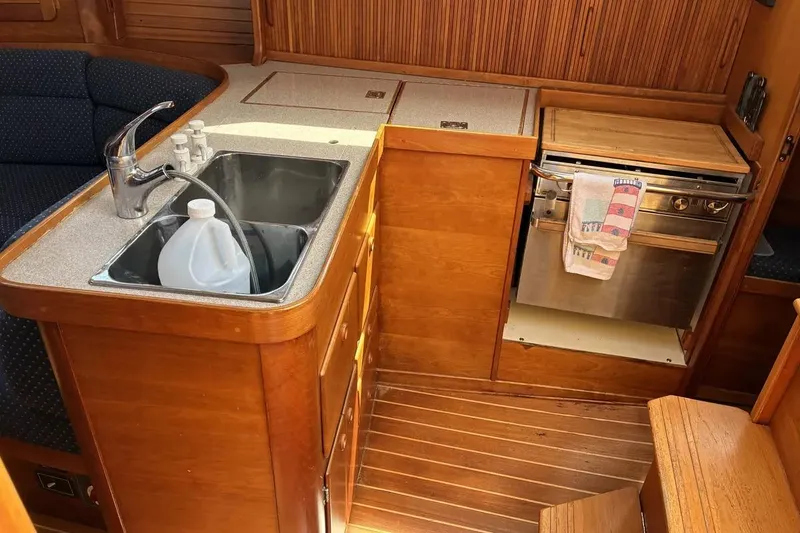 Slide: The Image of 1998 Sabre 36 yacht interior kitchen with sink, stove, and wooden cabinetry. - 5