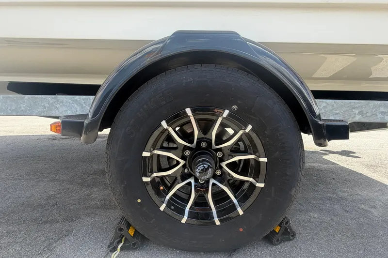 Slide: The Image of Trailer wheel of a 2015 Sea Ray 19 SPX boat on pavement. - 56