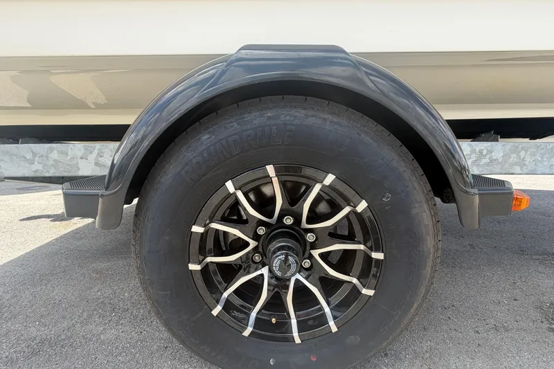 Slide: The Image of Trailer wheel of a 2015 Sea Ray 19 SPX boat on pavement. - 57
