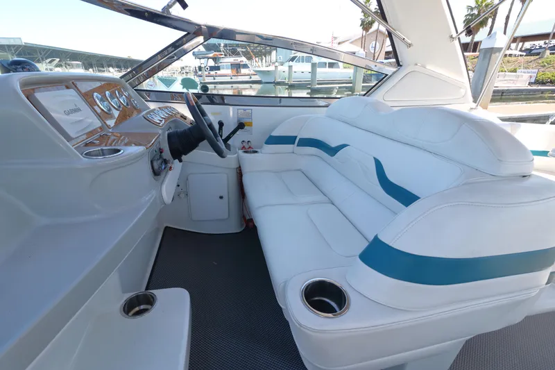 Slide: The Image of 2006 Formula 330 Sun Sport boat interior with white and blue seating, docked at marina. - 13