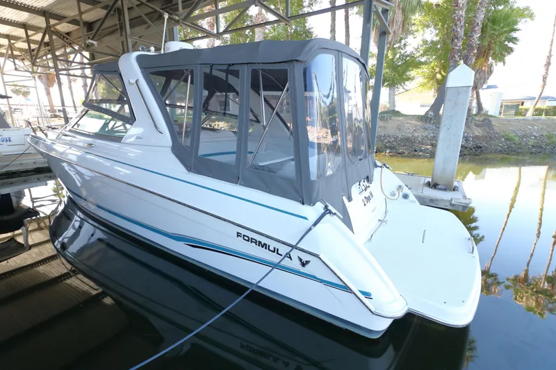 Slide: The Image of 2006 Formula 330 Sun Sport boat docked under a canopy, featuring sleek design and enclosed cockpit. - 5