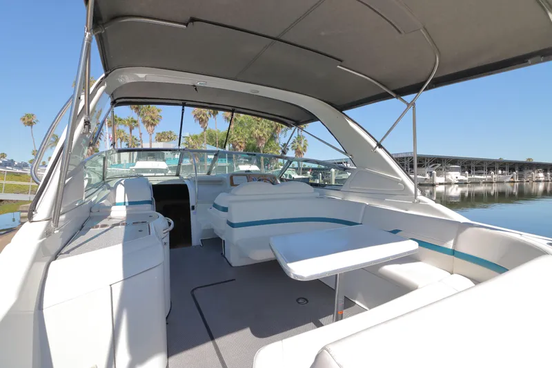 Slide: The Image of 2006 Formula 330 Sun Sport boat interior with seating and table, docked near palm trees. - 6