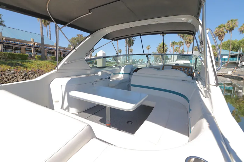 Slide: The Image of 2006 Formula 330 Sun Sport boat interior with seating and table, docked near palm trees. - 7