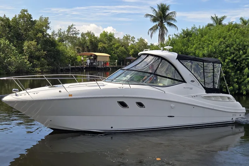 The Image of 2010 Sea Ray Sundancer 330 cruising on a calm river, surrounded by lush greenery. - 0