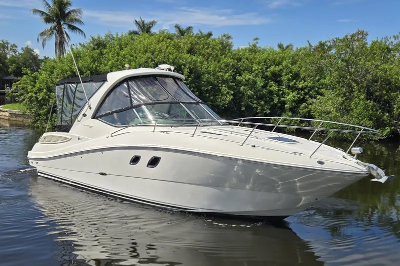 Slide: The Image of 2010 Sea Ray Sundancer 330 cruising on a calm waterway with lush greenery. - 1