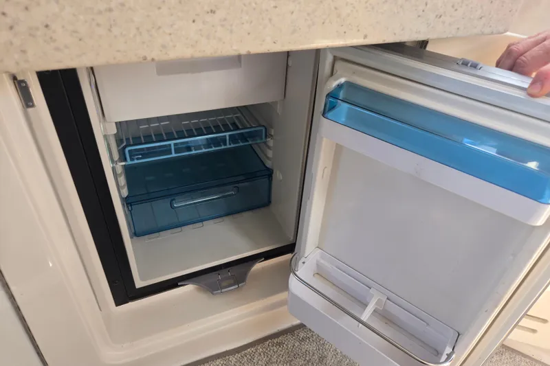 Slide: The Image of Open refrigerator inside 2010 Sea Ray Sundancer 330 yacht, featuring blue storage compartments. - 12