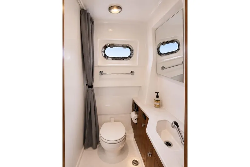 Slide: The Image of 2022 Pursuit S 358 Sport boat bathroom with toilet, sink, and porthole window. - 12