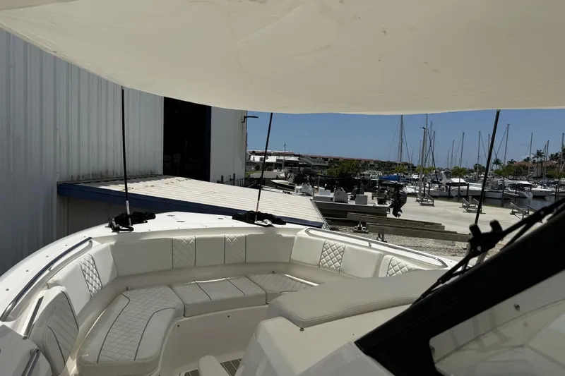 Slide: The Image of 2022 Pursuit S 358 Sport boat with luxurious seating, docked at a marina under a canopy. - 14