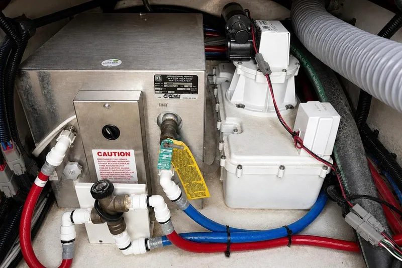 Slide: The Image of 2022 Pursuit S 358 Sport boat engine compartment with water heater and plumbing components. - 22