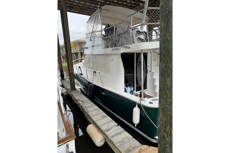 Slide: The Image of 2003 Mainship 390 Trawler docked under shelter, featuring green hull and white upper deck. - 13
