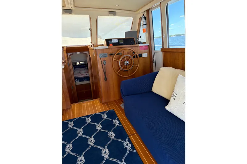 Slide: The Image of Interior of 2003 Mainship 390 Trawler with wooden helm, blue sofa, and nautical decor. - 15