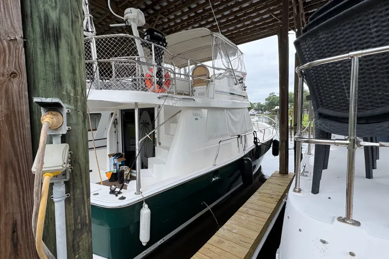 Slide: The Image of 2003 Mainship 390 Trawler docked under a covered marina, featuring upper deck and railing. - 5