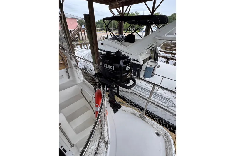 Slide: The Image of 2003 Mainship 390 Trawler with Suzuki outboard motor, docked under a wooden shelter. - 8