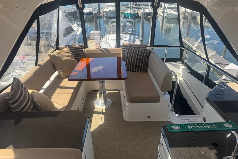 Slide: The Image of 2016 Sea Ray L590 Fly yacht interior with covered seating and table, docked at marina. - 45