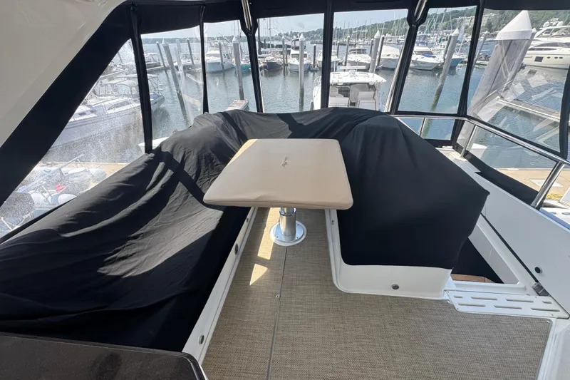 Slide: The Image of 2016 Sea Ray L590 Fly yacht interior with covered seating and table, docked at marina. - 5