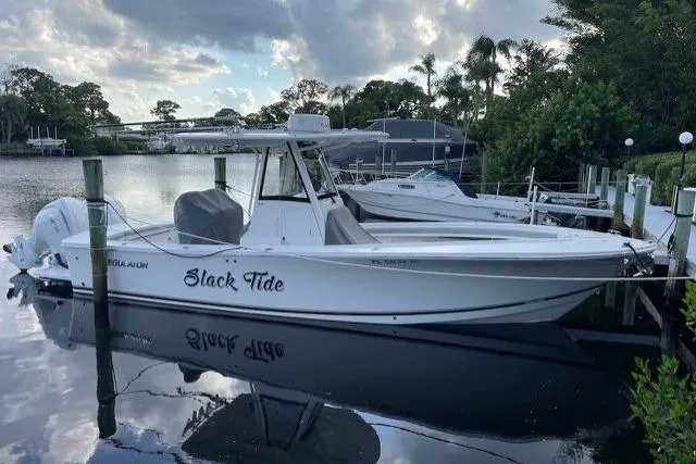 The Image of 2022 Regulator 28 boat named "Slack Tide" docked by a serene waterfront. - 0