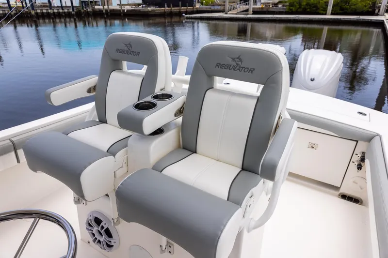 Slide: The Image of 2022 Regulator 28 boat seats with cup holders, docked by calm water. - 51