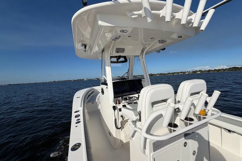 Slide: The Image of 2022 Regulator 28 boat interior with helm and rod holders on open water. - 12