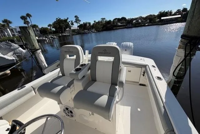Slide: The Image of 2022 Regulator 28 boat interior with dual seats, docked by a serene waterfront. - 16
