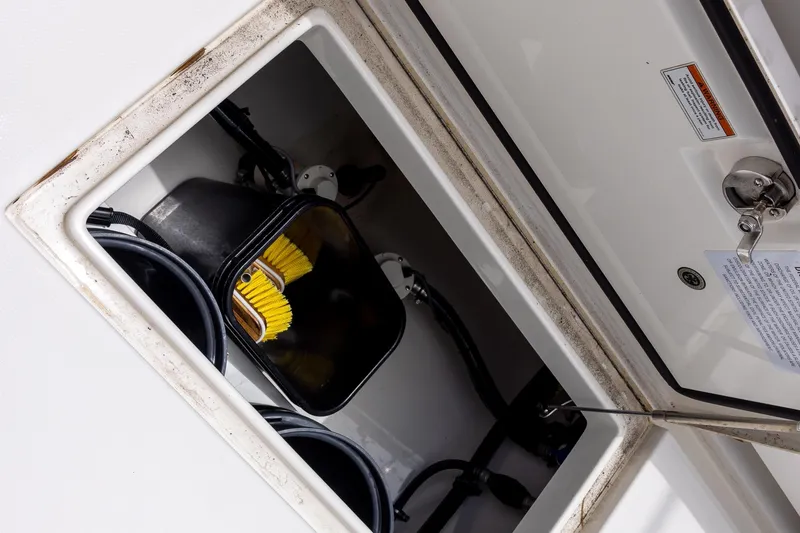 Slide: The Image of Storage compartment on a 2022 Regulator 28 boat, featuring a yellow brush and cables. - 49