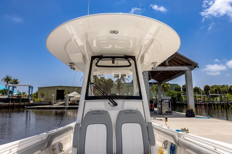 Slide: The Image of 2022 Regulator 28 boat at dock, showcasing helm and seating under clear blue sky. - 34
