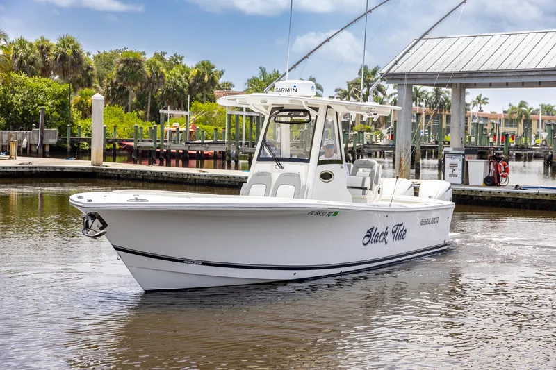 Slide: The Image of 2022 Regulator 28 boat docked in a marina, surrounded by lush greenery and clear skies. - 12