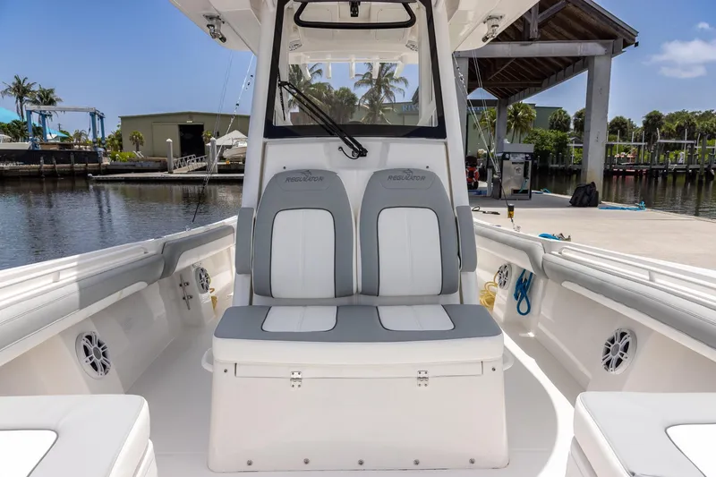 Slide: The Image of 2022 Regulator 28 boat interior with dual seats, docked by a marina. - 35