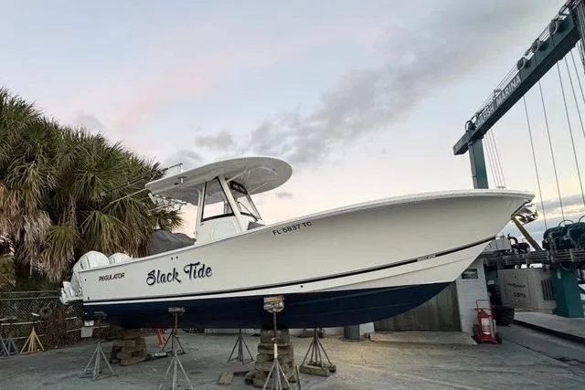 Slide: The Image of 2022 Regulator 28 boat named "Slack Tide" on dry dock, surrounded by palm trees. - 5