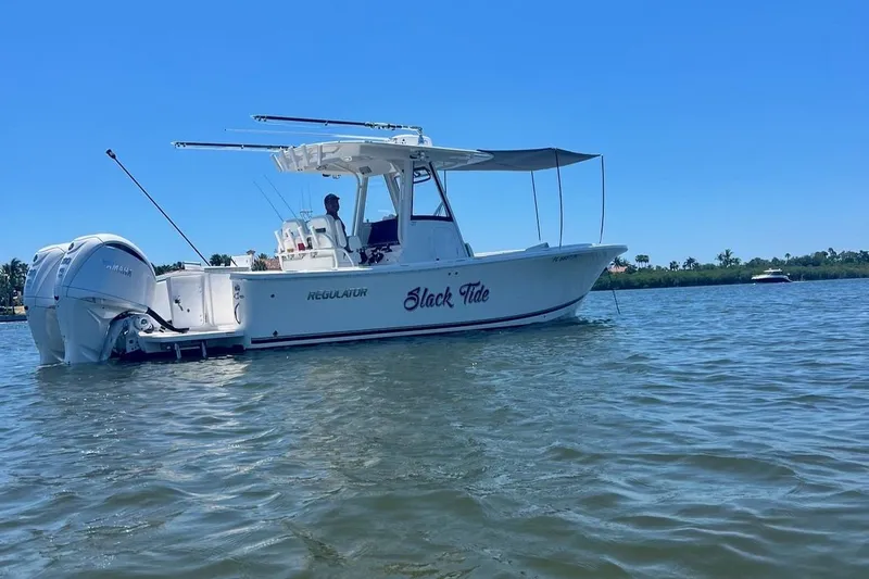 Slide: The Image of 2022 Regulator 28 boat named "Slack Tide" on calm water under clear blue sky. - 6