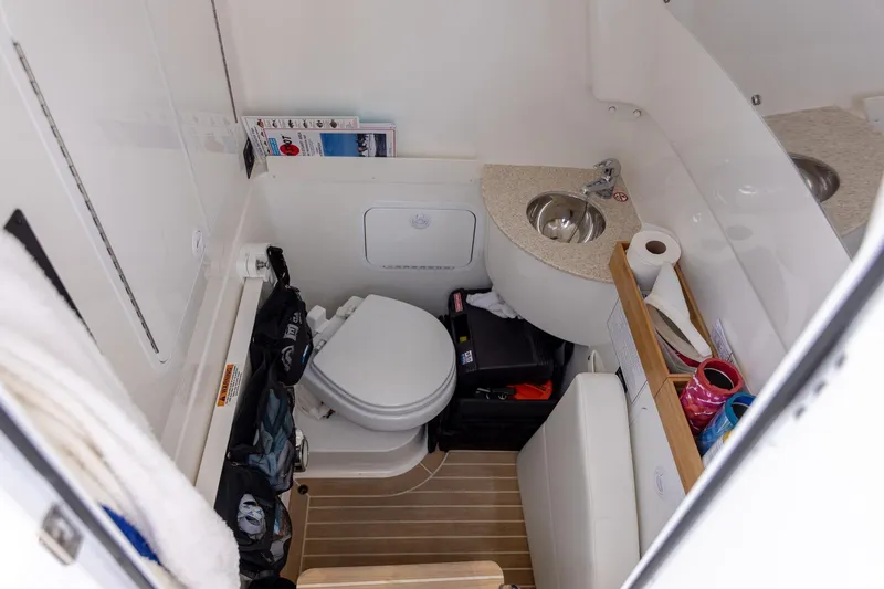 Slide: The Image of 2022 Regulator 28 boat interior bathroom with toilet, sink, and storage space. - 29