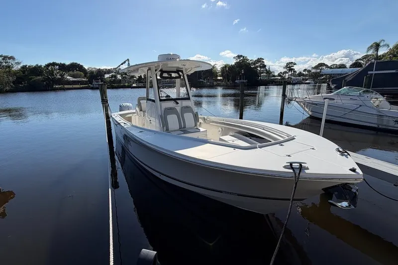 Slide: The Image of 2022 Regulator 28 boat docked on calm water under clear blue sky. - 9
