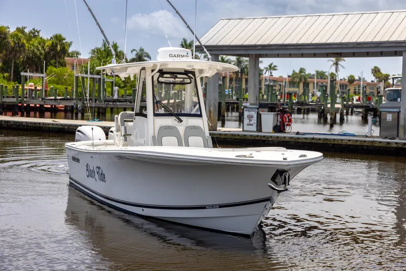 Slide: The Image of 2022 Regulator 28 boat docked at a marina with palm trees in the background. - 13