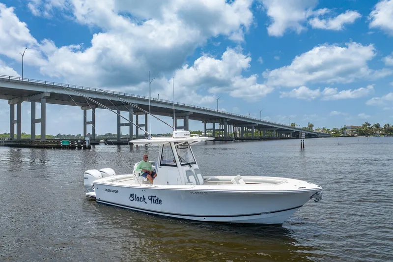 Slide: The Image of 2022 Regulator 28 boat on water near a bridge under a partly cloudy sky. - 5