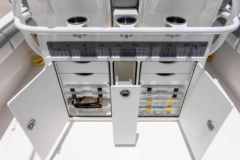 Slide: The Image of 2022 Regulator 28 boat storage compartments with open doors and organized tackle boxes. - 22