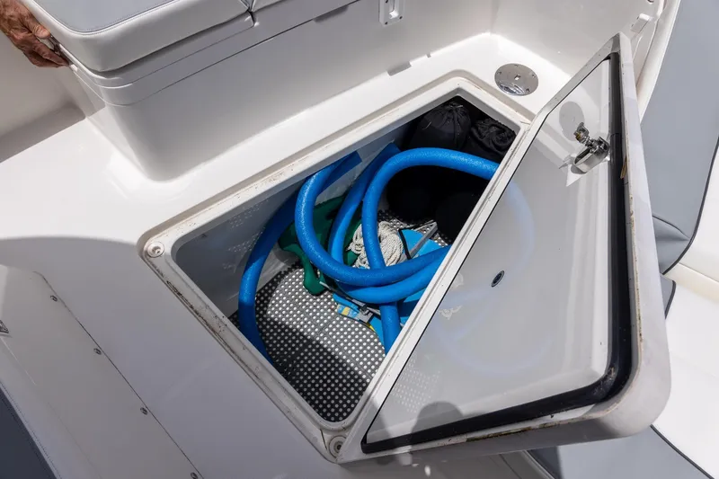 Slide: The Image of Storage compartment on a 2022 Regulator 28 boat, containing blue hoses and equipment. - 40