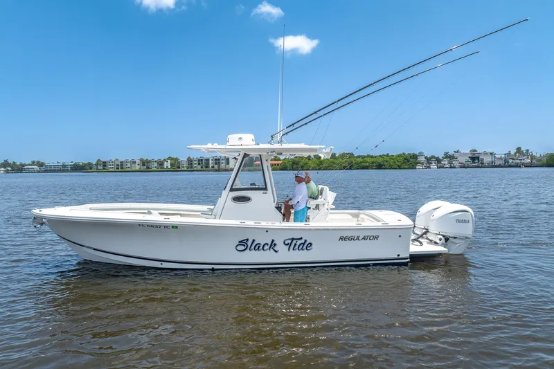 Slide: The Image of 2022 Regulator 28 boat named "Slack Tide" on calm water with fishing rods. - 4