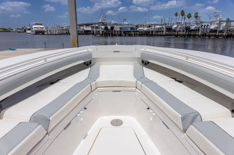 Slide: The Image of 2022 Regulator 28 boat interior with cushioned seating, docked at marina under blue sky. - 33