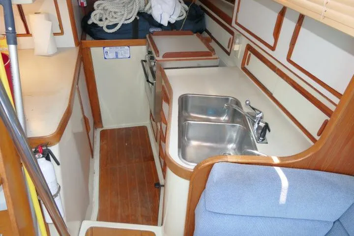 Slide: The Image of Compact kitchen area in a 1988 Irwin 38-2 sailboat with sink and wooden accents. - 10