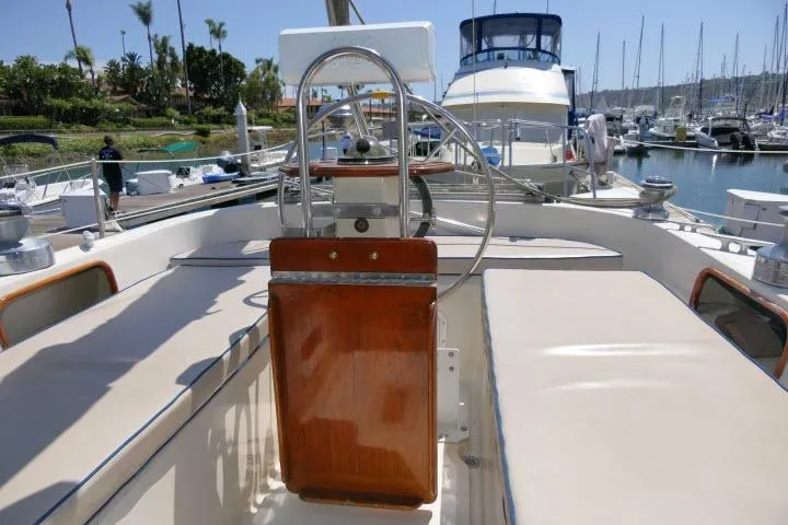 Slide: The Image of Cockpit of 1988 Irwin 38-2 sailboat with wooden helm and marina background. - 37