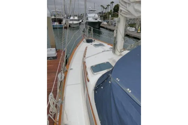 Slide: The Image of 1988 Irwin 38-2 sailboat docked at marina, featuring deck and blue cover. - 45