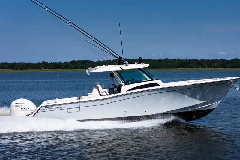Slide: The Image of 2025 Grady-White Canyon 386 boat cruising on a serene lake under a clear blue sky. - 1