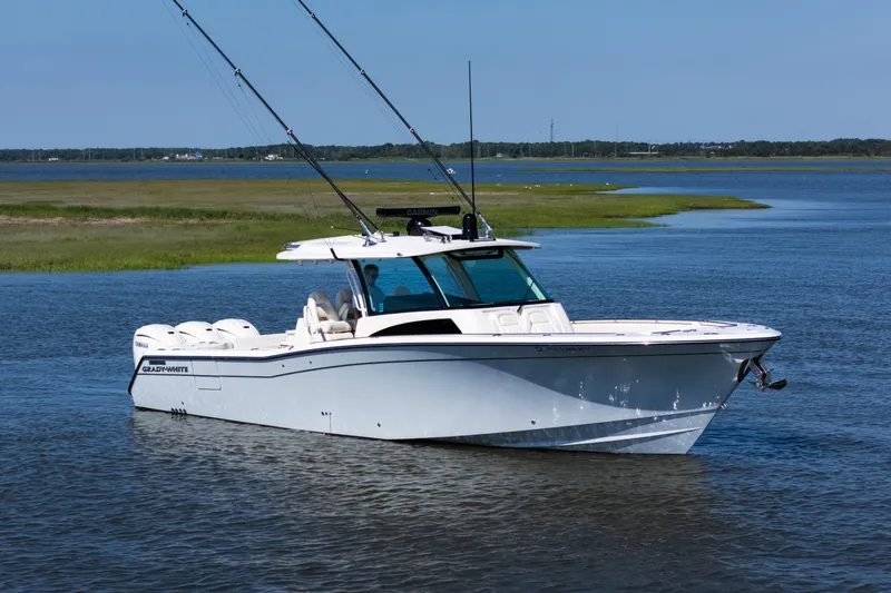 Slide: The Image of 2025 Grady-White Canyon 386 boat on calm water, featuring sleek design and fishing rods. - 4