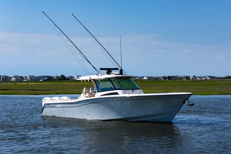 Slide: The Image of 2025 Grady-White Canyon 386 boat on calm water, with fishing rods, under clear blue sky. - 9